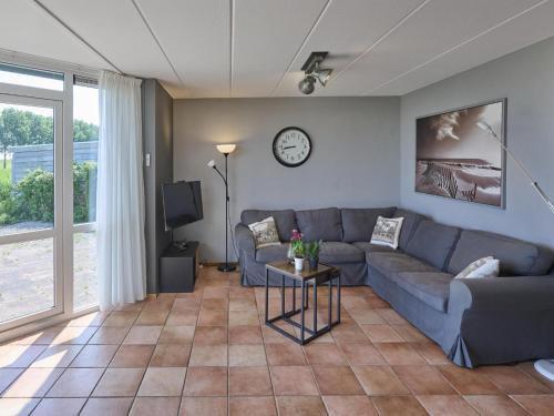a living room with a couch and a clock on the wall at Poldergeluk in Ooltgensplaat