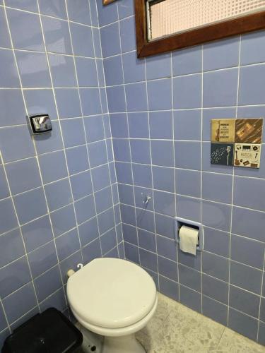 a bathroom with a toilet and blue tiled walls at Elegant House with Party Room in Santana do Livramento