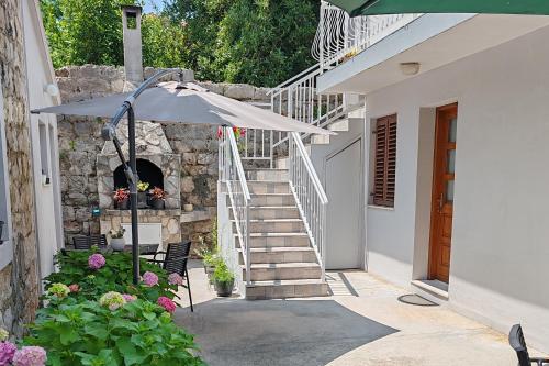 a patio with an umbrella and a stone fireplace at Apartments by the sea Zaton Veliki, Dubrovnik - 2107 in Zaton