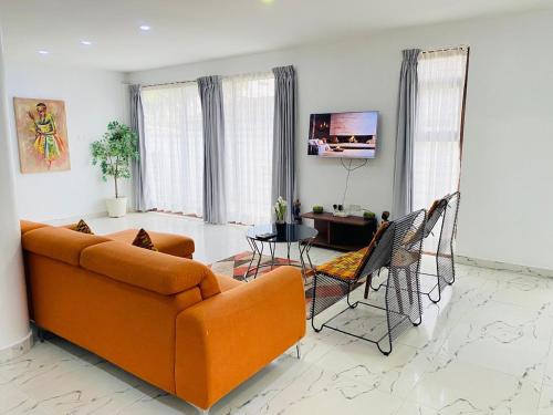 a living room with an orange couch and a table at Luxury Urban Villa 3V in Kumasi