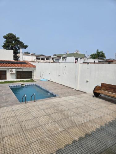 a swimming pool with a bench next to a white wall at Elegant House with Party Room in Santana do Livramento