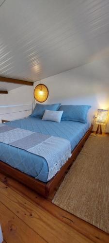 a bedroom with a bed with blue sheets and a lamp at Vila Prana - Chalé Paz - privacidade e vista infinita in Alto Paraíso de Goiás
