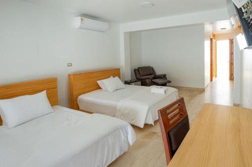 a hotel room with two beds and a chair at Hospedaje La Angostura in Ica