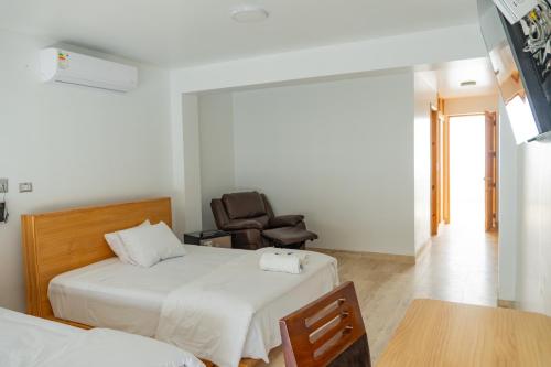 a bedroom with two beds and a chair and a table at Hospedaje La Angostura in Ica