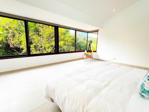 a white bedroom with large windows and a bed at Exclusive Villa with private pool, Jungle and Golf views - 8 Min Walk to the Beach in Puerto Aventuras