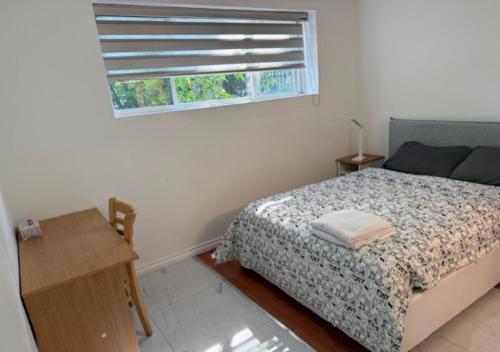 a bedroom with a bed and a window and a table at Exclusive Offer - A special deal ending soon!! Super Nice Location - Very close to YVR Airport and shopping center & easy transportation in Vancouver