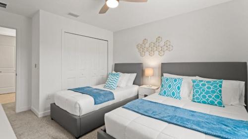 a bedroom with two beds with blue and white pillows at Stunning Townhouses 5 Minutes away Disney! in Kissimmee