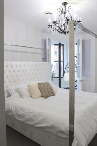 a bedroom with a large white bed with a chandelier at Beautiful 2 BED 2 BATH Soaker Tub in Albany