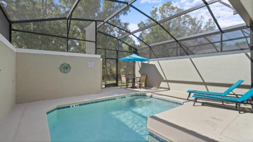 a swimming pool with two chairs and an umbrella at Stunning Townhouses 5 Minutes away Disney! in Kissimmee