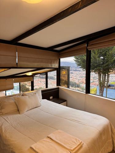 a bedroom with a large bed and large windows at Azotea Suites & Apartments in Cuenca