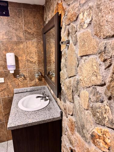 a stone bathroom with a sink and a stone wall at Azotea Suites & Apartments in Cuenca