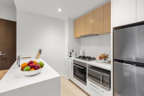 a white kitchen with a bowl of fruit on a counter at Astra Apartments Southbank Prima Pearl in Melbourne