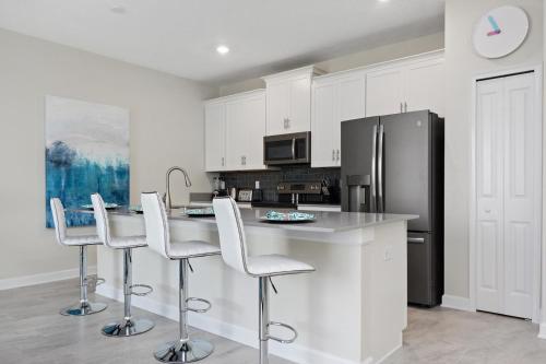 a kitchen with white cabinets and a stainless steel refrigerator at Stunning Townhouses 5 Minutes away Disney! in Kissimmee