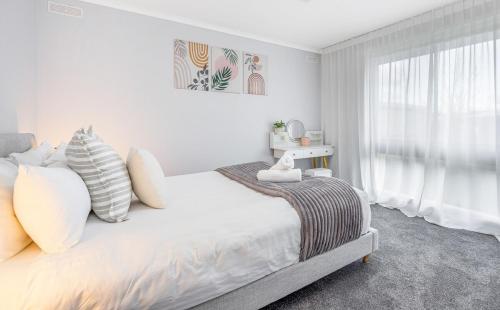 a white bedroom with a bed with pillows and a window at Bendigo Signature Accommodation on Garden Court in North Bendigo Junction