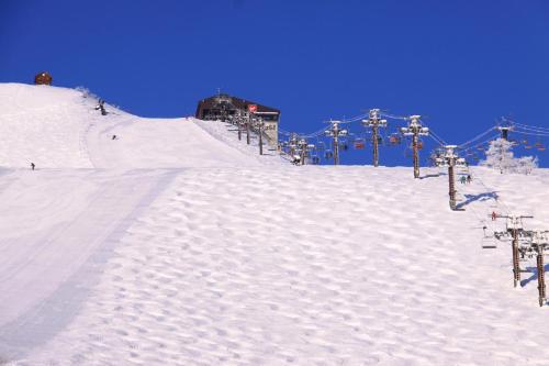a snow covered ski slope with a ski lift at Hotel Hakuba in Hakuba