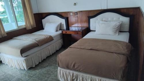 two beds sitting next to each other in a room at Hotel Wailiti in Maumere