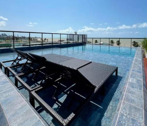 a large swimming pool with chairs in the water at Flat sofisticado na Praia do Cabo Branco 4 pessoas in Tambaú