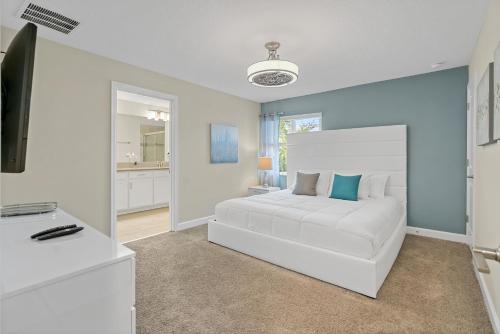 a white bedroom with a white bed and a television at Stunning Townhouses 5 Minutes away Disney! in Kissimmee
