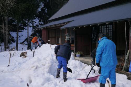 a group of people shoveling snow from a snow bank at 生きる宿 