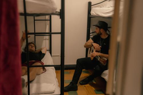 two men sitting on bunk beds in a room at Havana Dance School & Hostel in Cali