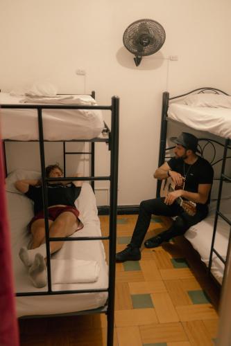 two men sitting on bunk beds in a room at Havana Dance School & Hostel in Cali