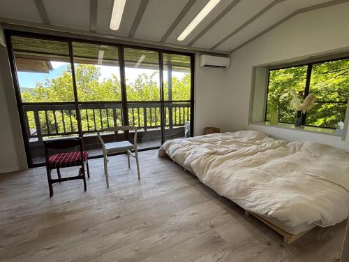 a bedroom with a bed and a table and windows at Oyado S in Hakone