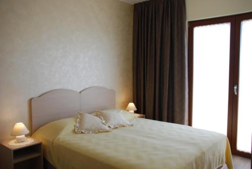 a bedroom with a bed with white sheets and a window at Rooms Edda in Umag