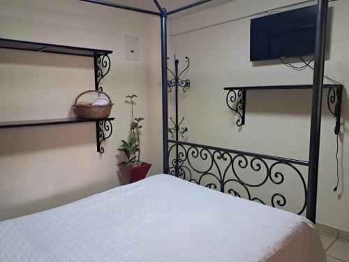 a bedroom with a white bed and a tv at Hotel Antigua Encomienda in Atlixco