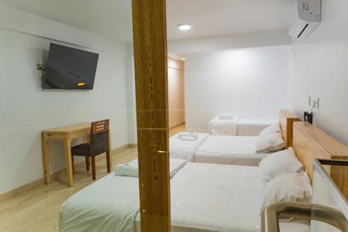 a room with two beds and a desk and a tv at Hospedaje La Angostura in Ica