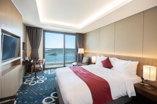 a hotel room with a large bed and a television at Ramada Plaza by Wyndham Dolsan Yeosu in Yeosu