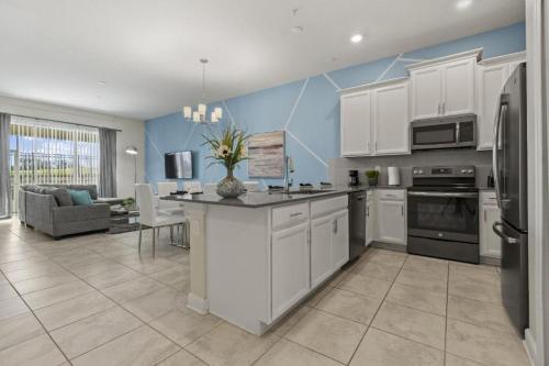 a kitchen with white cabinets and a living room at Lovely apartments 18 Minutes away from Disney! in Kissimmee