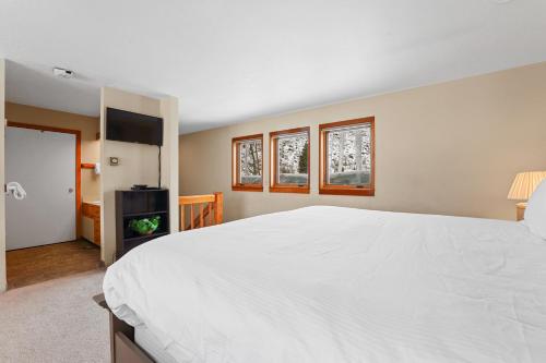 a bedroom with a large white bed and two windows at Quicksilver 1658 by Summit County Mountain Retreats in Keystone