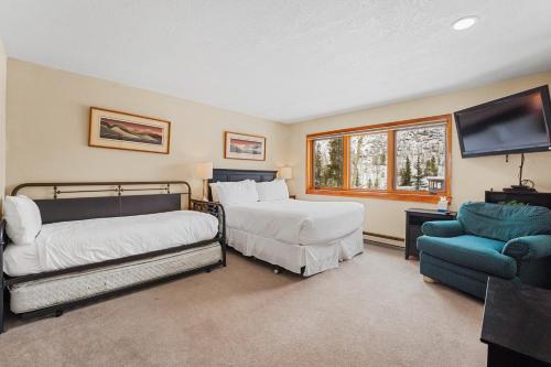 a bedroom with two beds and a tv and a chair at Quicksilver 1658 by Summit County Mountain Retreats in Keystone