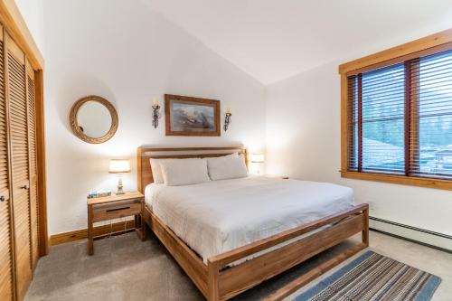 ein Schlafzimmer mit einem Bett, einem Spiegel und einem Fenster in der Unterkunft Ski Tip 8715 by Summit County Mountain Retreats in Snake River Health Services Incorporated Heliport