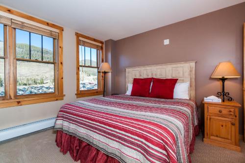 a bedroom with a bed with red pillows and windows at Buffalo Lodge 8391 by Summit County Mountain Retreats in Snake River Health Services Incorporated Heliport