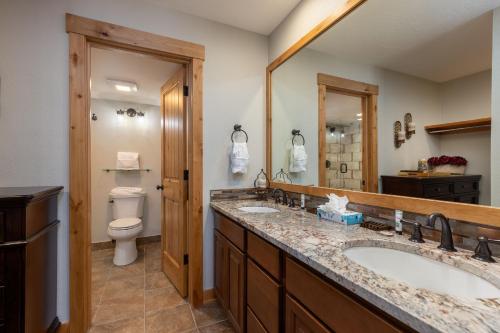 ein Badezimmer mit zwei Waschbecken und einer Toilette und einem Spiegel in der Unterkunft Pines 2158 by Summit County Mountain Retreats in Keystone