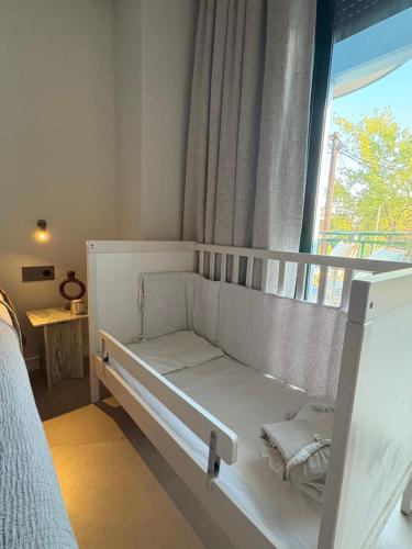 a white crib in a room with a window at Nikiti Blue house 30m from the beach with sea view in Nikiti