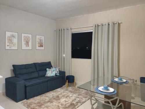 a living room with a blue couch and a glass table at Flat novo - Central - Vila Exposição - Garantia de conforto e satisfação in Montes Claros