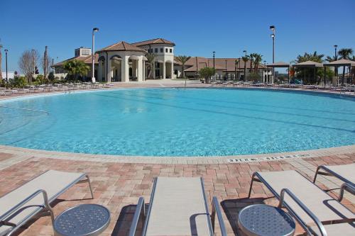 a large swimming pool with chairs and a building at Lovely apartments 18 Minutes away from Disney! in Kissimmee