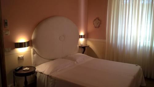 a bedroom with a white bed and a window at Il Rondò Boutique Hotel in Montepulciano