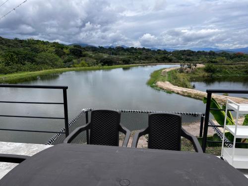 a table with two chairs and a view of a river at Cabaña Finca La Manuela1 in Garzón