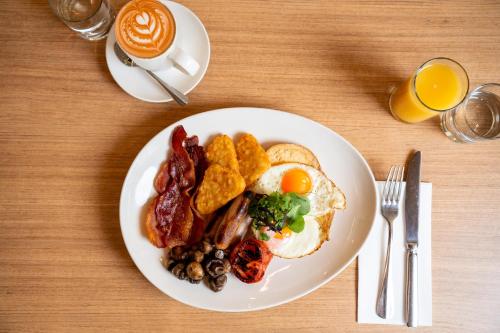 um prato branco de pequeno-almoço com ovos, bacon e torradas em Mercure Newcastle Airport em Newcastle
