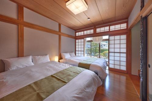 a bedroom with two beds in a room with windows at IZA cominca 萬 in Kameoka