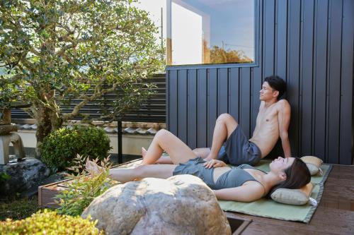 two people sitting on a blanket in a garden at IZA cominca 萬 in Kameoka