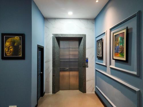 a hallway with blue walls and a door with paintings at BKK Concept Hotel in Phnom Penh