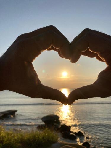 a pair of hands in the shape of a heart over a sunset at Purnima Resort Neil Island in Neil Island