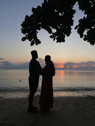 a man and a woman standing on the beach at sunset at Purnima Resort Neil Island in Neil Island