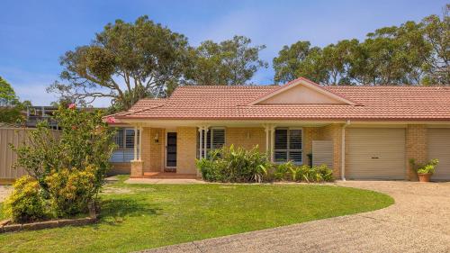 a yellow house with a yard in front of it at Chill Out at Fingal Jellicoe Close in Fingal Bay