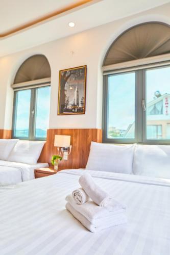 a bedroom with two beds with towels on it at Lotus Hotel Đà Lạt in Da Lat