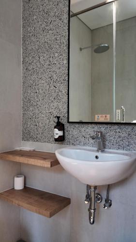 a bathroom with a white sink and a mirror at Jambuluwuk Bromo Poshtel in Pasuruan